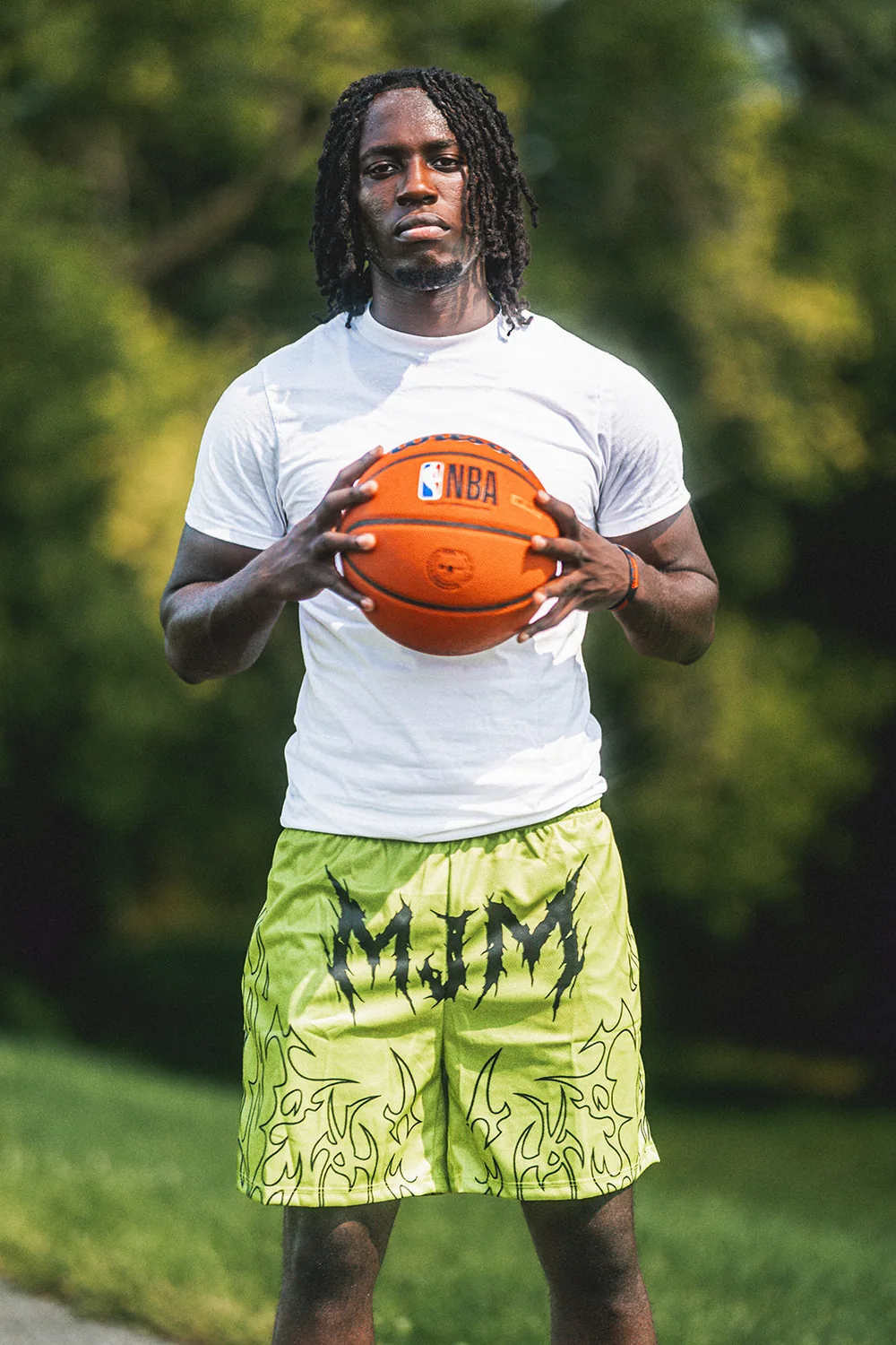 MJM Hoops athlete holding basketball in branded shorts